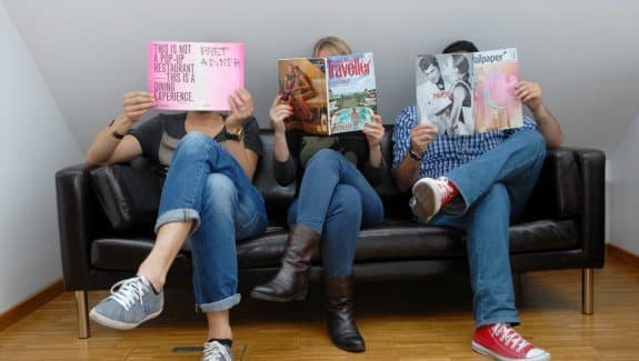 Drei Menschen sitzen auf dem Sofa und schmökern in Zeitschriften – Inspiration für Pressebilder