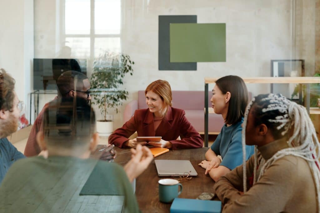 Menschen mehrerer Nationalitäten sitzen fröhlich an einem Meetingtisch