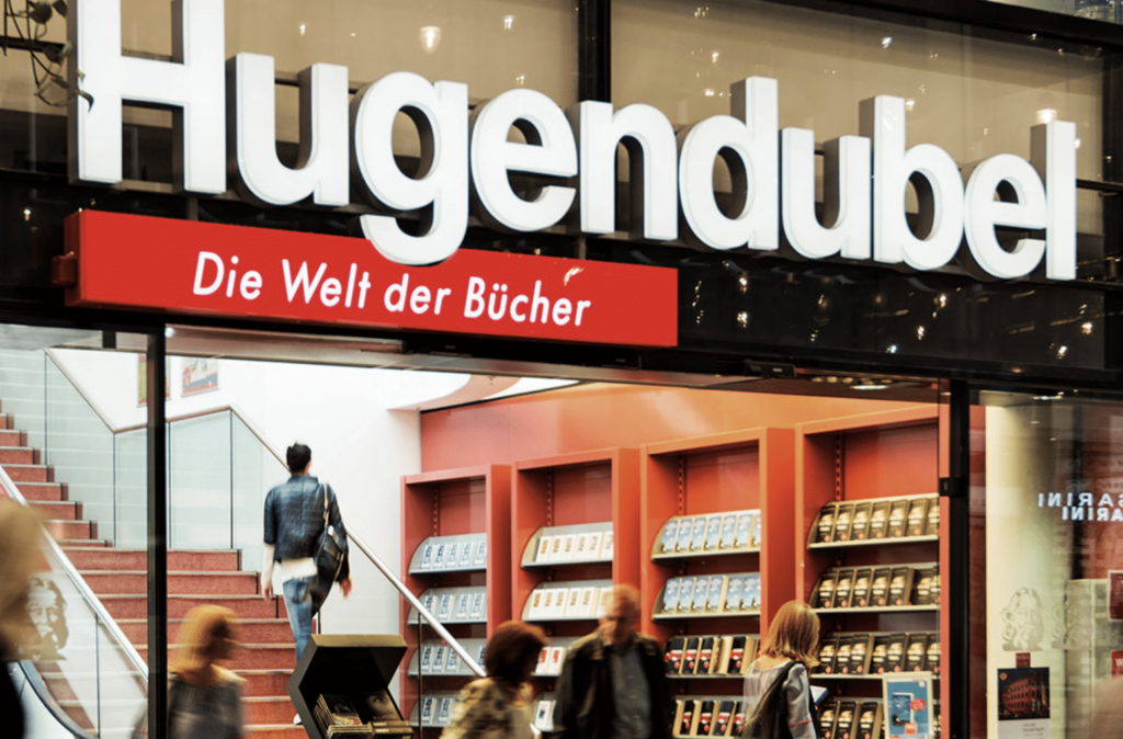 Eine Aufnahme einer Hugendubel Filiale, mit Fokus auf dem Slogan "Hugendubel-Die Welt der Bücher". 