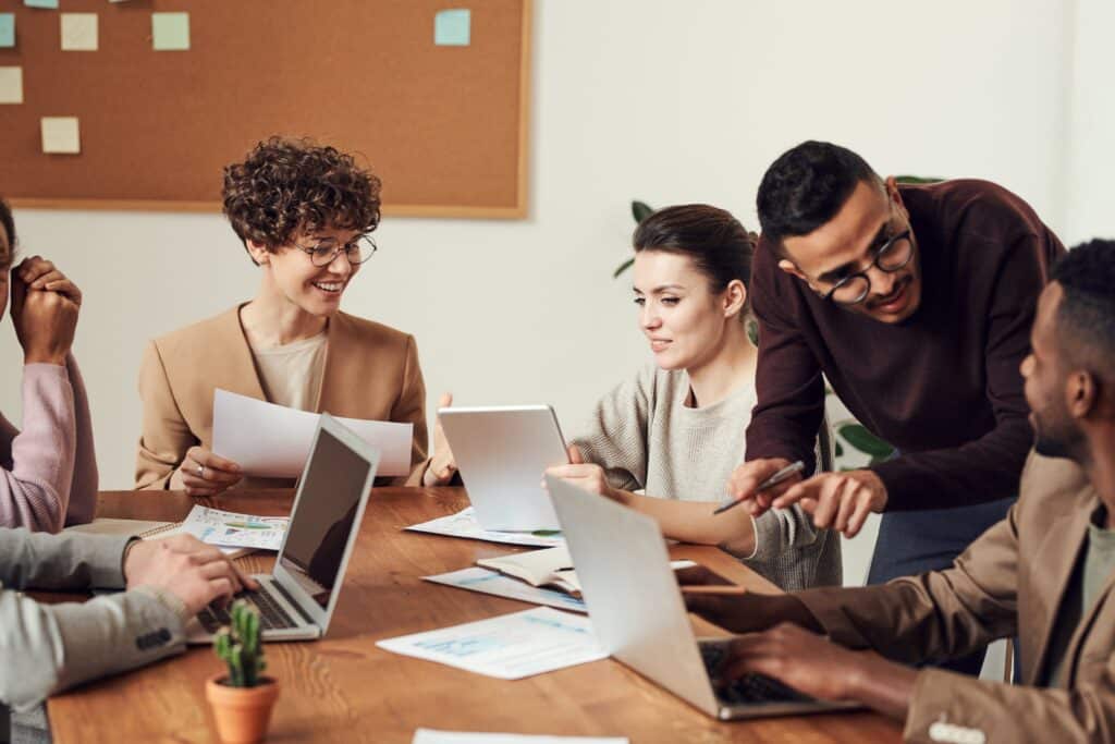 Ein Tisch an dem Mitarbeiter und Mitarbeiterinnen miteinander arbeiten